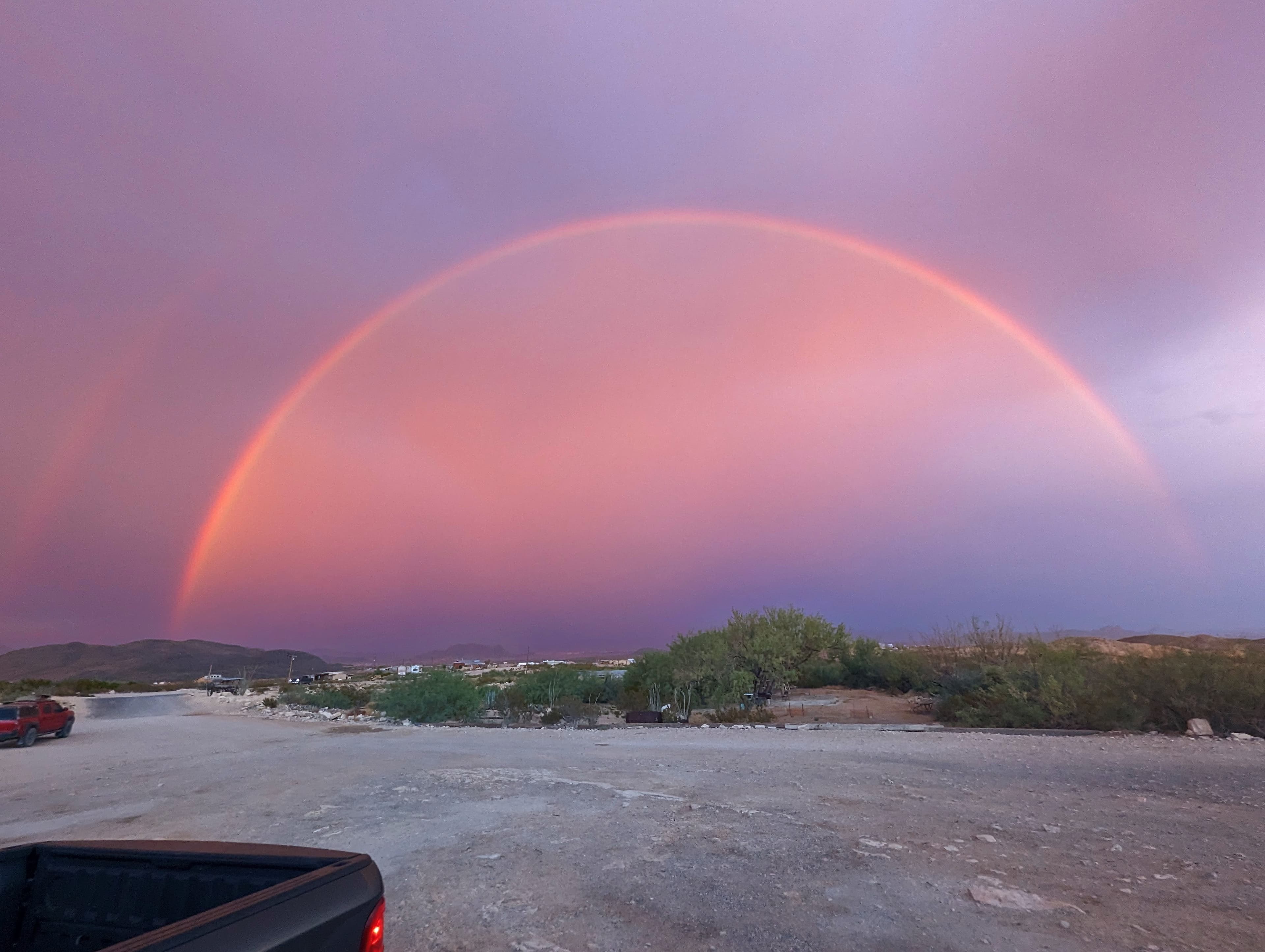 A double rainbow arcs over the desert sky in Terlingua, Texas at sunset